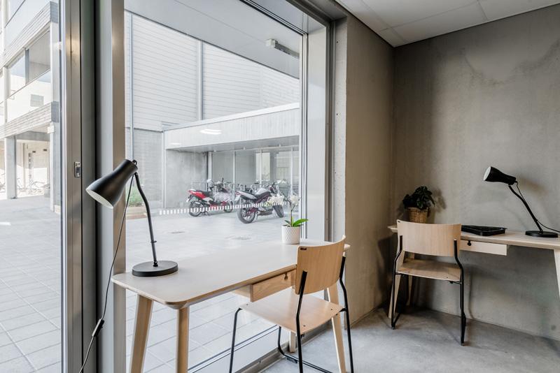 Two desks in a room. Big window towards the street. Room is in a street level.