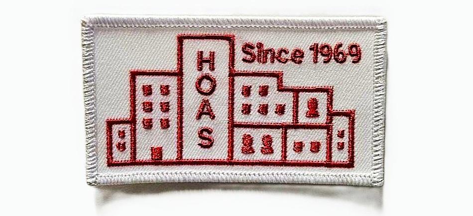 The photo shows a white Hoas overalls patch featuring a red logo and the text "Since 1969."